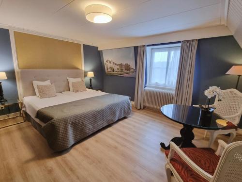 a bedroom with a bed and a table and a window at Hotel Brull in Mechelen
