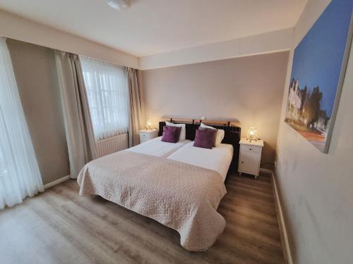 a bedroom with a large white bed with purple pillows at Hotel Brull in Mechelen