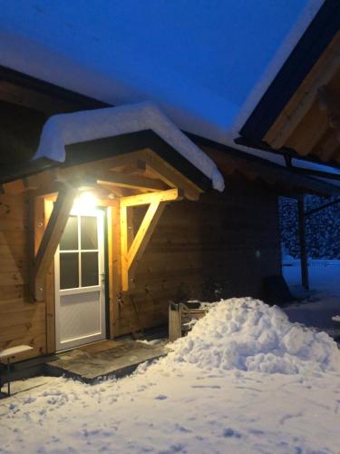a snow covered cabin with a light on the door at MyHolzhaus - zum Wohlfühlen in Gröbming