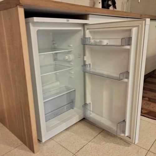 an empty refrigerator with its door open in a kitchen at Monolocale con veranda e giardino a Rio Marina in Rio Marina