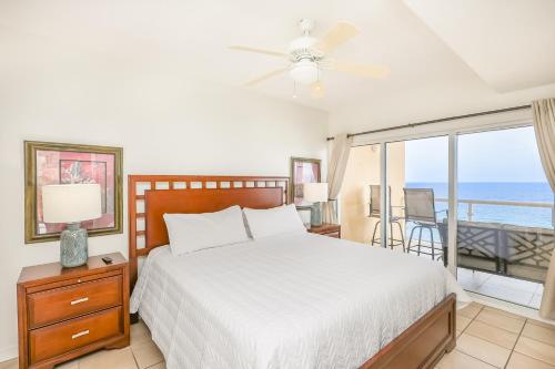 a bedroom with a bed and a balcony with the ocean at Emerald Isle Gulf Front 3B Condo - 1208 in Pensacola Beach