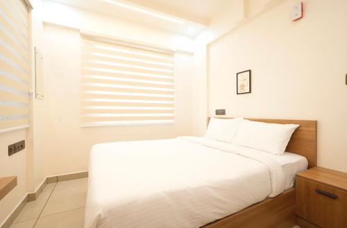 a bedroom with a white bed and a window at Visaj inn in Kakkanad