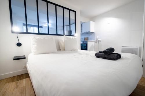 une chambre avec un grand lit blanc avec une grande fenêtre dans l'établissement Cocon urbain PARIS, à Paris