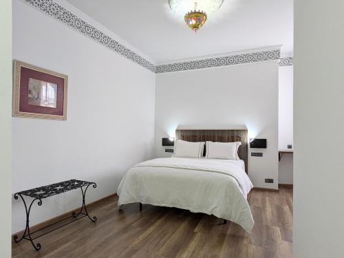 a white bedroom with a large bed and a chandelier at Hôtel Les Remparts in Azemmour