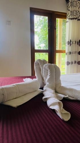 a pile of towels laying on a bed with a window at River paradise safari house with cooking class in Udawalawe