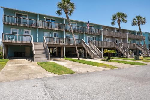 a large apartment building with stairs and palm trees at Sandy Dreams - 2B Townhome in Pensacola Beach