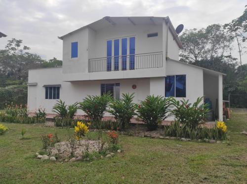 a white house with blue windows and a yard at Villas Campestres las Heliconias in Villavicencio