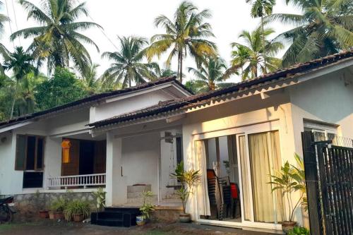 a white house with palm trees in the background at Nakshatra Villa - A Relaxing Villa in Alibag in Revadanda