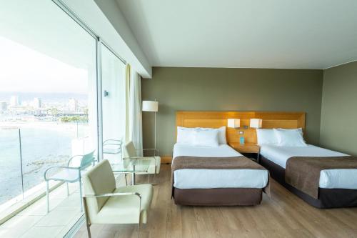 a hotel room with two beds and a large window at Terrado Suites Antofagasta in Antofagasta
