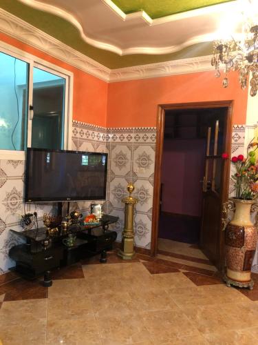 Una sala de estar con un televisor de pantalla plana en una pared. en Charming quiet appartement, very good location, en Sidi Slimane