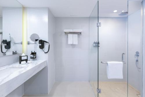 a white bathroom with a shower and a glass door at INNSiDE by Meliá Yogyakarta in Yogyakarta