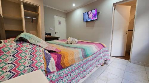 a bedroom with two beds and a tv on the wall at Hotel Firenze in Necochea