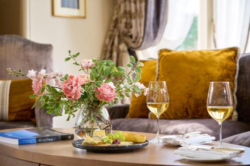a table with a vase of flowers and two glasses of wine at Dromoland Castle in Newmarket on Fergus
