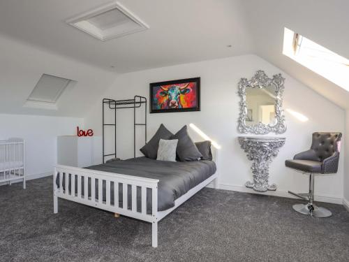 a bedroom with a bed with a mirror and a chair at Ty'n Ffridd in Pwllheli