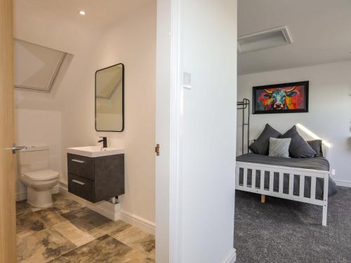 a bathroom with a bed and a sink and a mirror at Ty'n Ffridd in Pwllheli