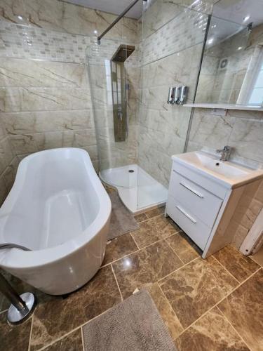 a bathroom with a white tub and a sink at Idyllic Cottage in Garforth