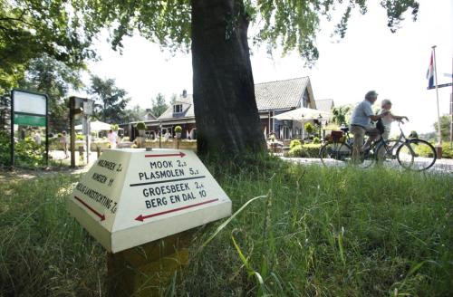a sign sitting in the grass next to a tree at Herberg Restaurant 't Zwaantje in Mook