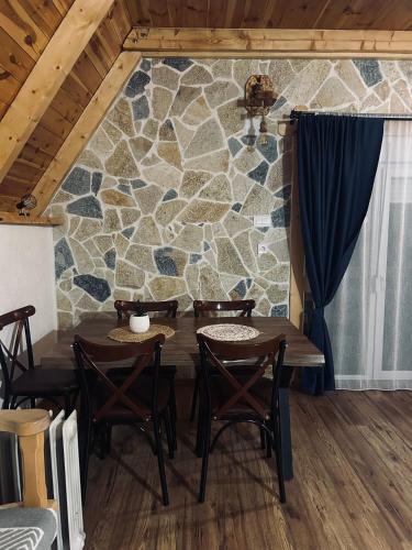 a table and chairs in a room with a stone wall at Nomad Lodge Zminica in Žabljak