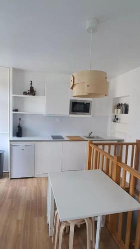 une cuisine blanche avec une table et des chaises blanches dans l'établissement Charmant nid au cœur de Paris, à Paris