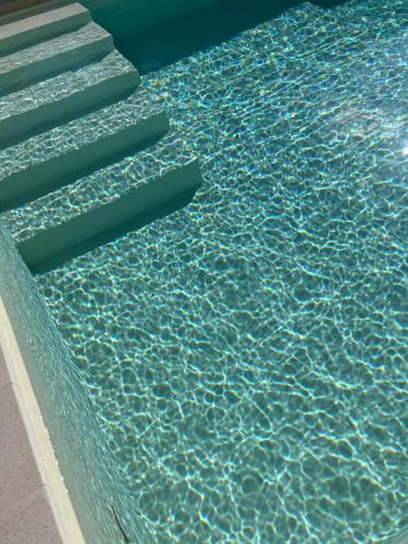 a swimming pool with blue water and stairs in it at Trulli Milena in Putignano