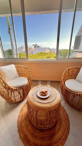 a room with three wicker chairs and a table at SunSet Appart' in Saint-Pierre