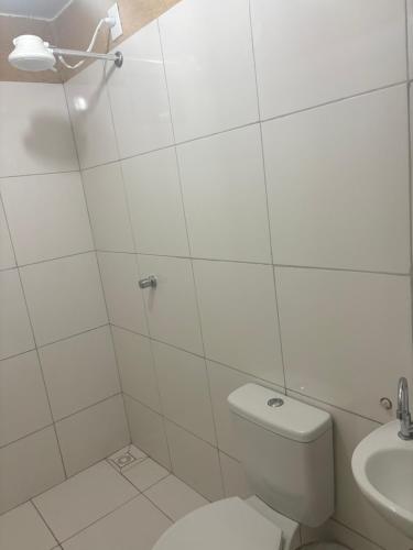 a white bathroom with a toilet and a sink at H one Hotel in Goiânia