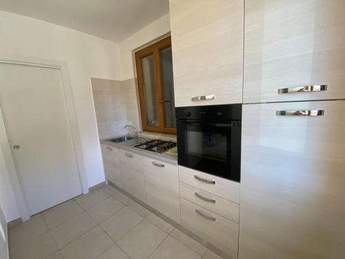 a kitchen with white cabinets and a black appliance at La Casetta in LʼAquila