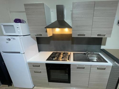 a kitchen with a white refrigerator and a stove at Le relax de panne in De Panne