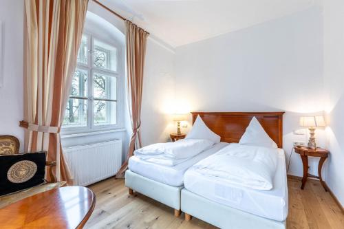a bedroom with a white bed and a window at Apartments am Schloss Mühldorf in Feldkirchen an der Donau