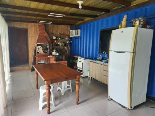 a kitchen with a wooden table and a refrigerator at Casa Container in São Francisco do Sul