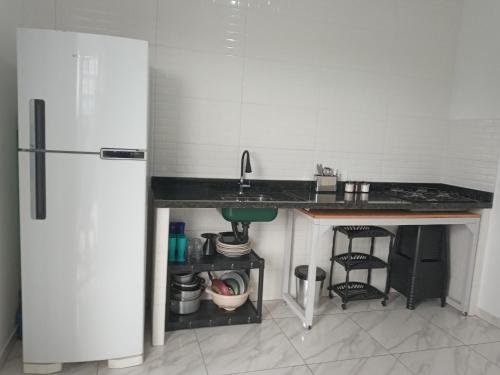 a kitchen with a counter and a sink and a refrigerator at Guará Apart 4 in Guaratuba