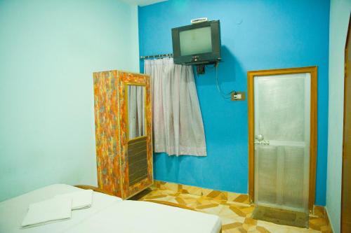 Habitación con TV, cama y espejo. en Hotel Ganesha, en Varanasi