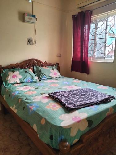 a bedroom with a bed with a floral comforter at Aadhiran residency 2BHK in Tiruvannāmalai