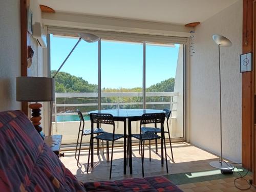 une table et des chaises dans une pièce avec une grande fenêtre dans l'établissement Studio à deux pas de la mer, au Grau-du-Roi