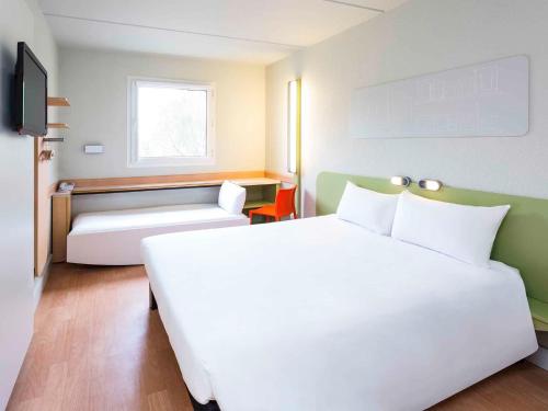 a hotel room with a large white bed and a couch at Ibis Budget Madrid Alcorcón Móstoles in Alcorcón