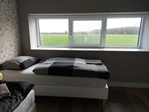 a bedroom with two beds in front of a window at Raafjeshof - Vakantiewoning in Kuilenburg