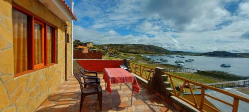 a balcony with a table and chairs and a view of the water at Willka Uta in Comunidad Challapampa