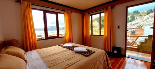 a bedroom with a bed and large windows at Willka Uta in Comunidad Challapampa