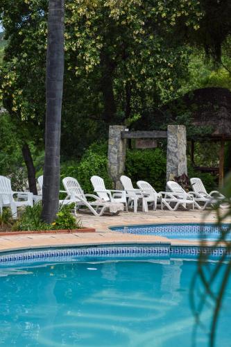 a group of white chairs and a swimming pool at Hotel Del Dique in Coronel Moldes