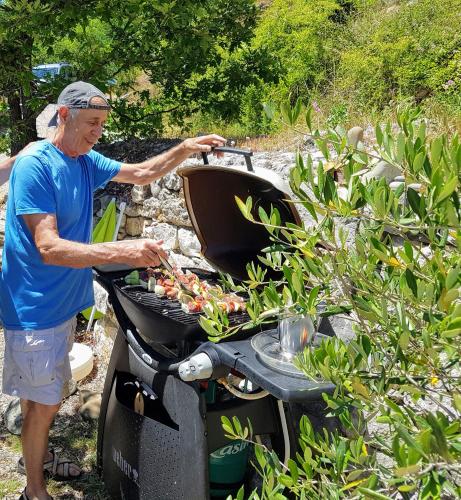 an older man is cooking on a grill at Studio idealement situe pour decouvrir le Verdon in Castellane