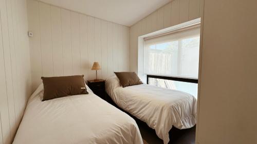 two beds in a room with a window at Casa Molino - Casa en Complejo Land Houses A Dos cuadras de Cruz del Sur, Chapadmalal - Hola Sur in Chapadmalal
