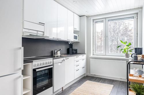 a kitchen with white appliances and a window at Cozy 1BR Apartment next to the Beach with Free Parking in Lahti