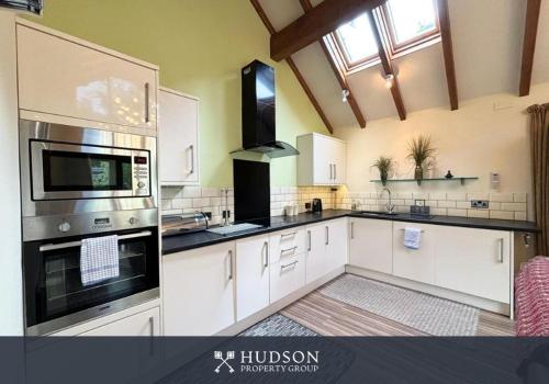 a large kitchen with white cabinets and a window at Beautiful Cottage in the Heart of Shrewsbury in Shrewsbury