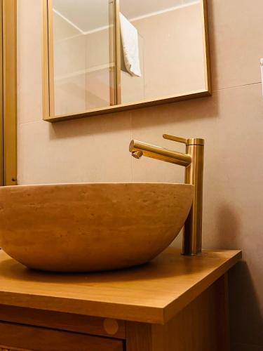 a bathroom sink with a copper faucet and a mirror at La Suite Marrakech, Balneo et Parking in Obernai