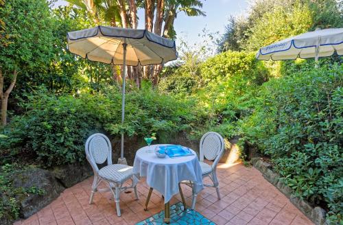 a patio with a table and chairs and an umbrella at Corallo Blu Hotel De Charme - Sea & Spa access in Ischia