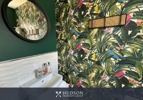 a bathroom with a mirror and a sink with a tropical wallpaper at 3 Bedroom Modern Property with Parking in Shrewsbury
