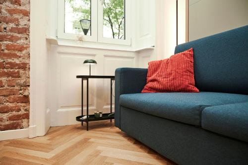 a blue couch with a red pillow and a table at MILANO URBAN FLATS Suite Sanzio 20 - Vicino a Duomo, Stadio e Fiera in Milan