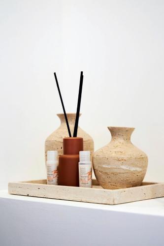 a shelf with three vases and candles on it at MILANO URBAN FLATS Suite Sanzio 20 - Vicino a Duomo, Stadio e Fiera in Milan