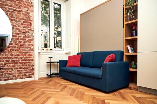 a blue couch with red pillows in a living room at MILANO URBAN FLATS Suite Sanzio 20 - Vicino a Duomo, Stadio e Fiera in Milan
