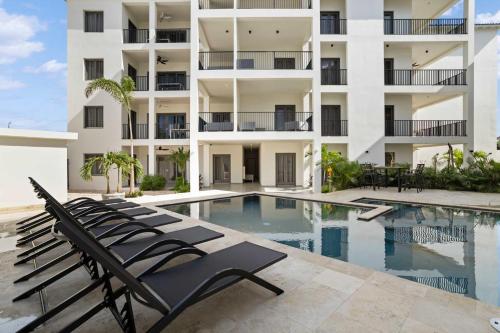 a swimming pool with lounge chairs in front of a building at Bonaire Beach Apartment 5 with shared pool and diving facilities in Kralendijk
